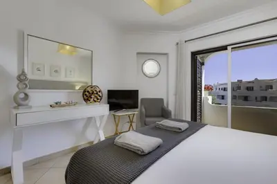 a bedroom with a bed and a desk and a window at CLUB ALBUFEIRA - 2 bedroom apartment, air conditioning and pools in Albufeira