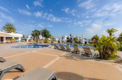 a resort pool with lounge chairs and palm trees at CLUB ALBUFEIRA - 2 bedroom apartment, air conditioning and pools in Albufeira