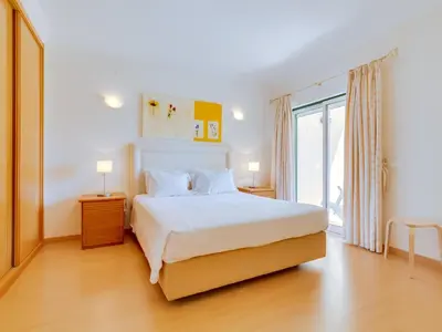 a bedroom with a white bed and a large window at 1 bdr apartment with pool next to Laguna Golf Course in Vilamoura
