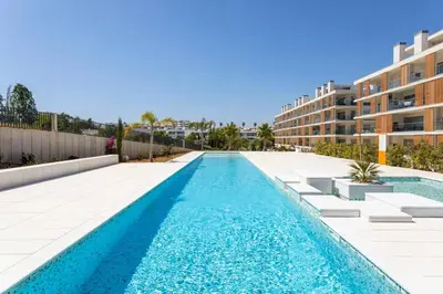 a swimming pool with blue water in front of a building at Casa Verde in Albufeira