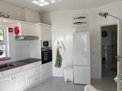 a kitchen with white cabinets and a white refrigerator at Solar dos Lirios in Loulé