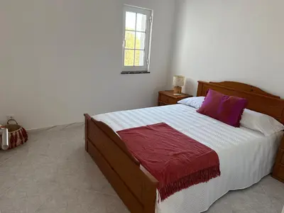 a bedroom with a large wooden bed with purple pillows at Solar dos Lirios in Loulé