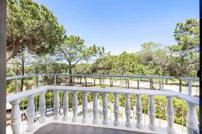a balcony with white railings and trees at Villa Melvin in Quarteira