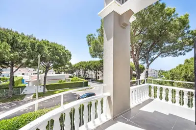 a balcony with a white railing and trees at Villa Melvin in Quarteira