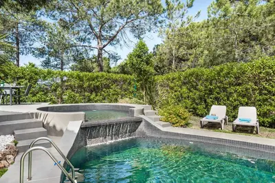 a pool with a waterfall and two chairs in a backyard at Villa Melvin in Quarteira