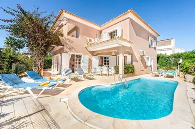 a villa with a swimming pool in front of a house at Villa Casanova Golf in Quarteira