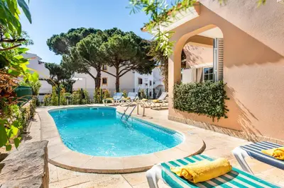 a swimming pool with two lounge chairs and a building at Villa Casanova Golf in Quarteira