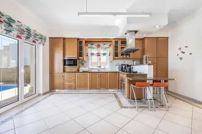 a kitchen with wooden cabinets and a large window at Villa Sunflower in Albufeira