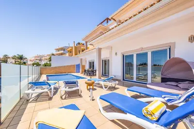 a patio with blue chairs and a swimming pool at Villa Sunflower in Albufeira
