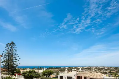 a view of a white house and the ocean at Villa Barbara in Albufeira