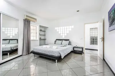 a white bedroom with a bed and a mirror at Villa Mogan in Albufeira