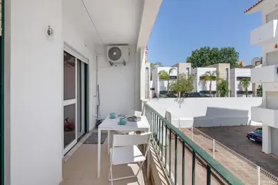 a balcony with a table and chairs on a building at Excellent Apartment in Olhos D´Água in Olhos de Água