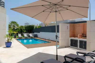 a patio with an umbrella and a swimming pool at Villa Velluto in Albufeira