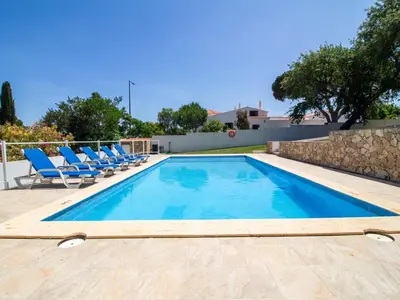 a swimming pool with blue chairs next to a wall at Vila Paço no Vale by Stay ici Algarve Holiday Rental in Albufeira