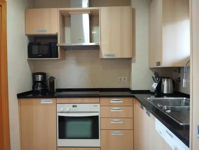 a small kitchen with wooden cabinets and a sink at Barracuda dom in Albufeira
