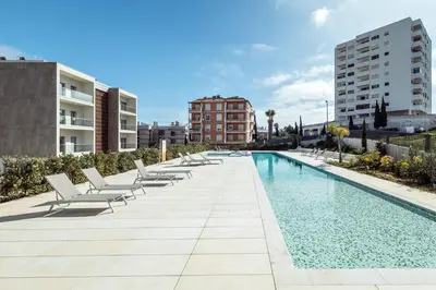 an overhead view of a swimming pool with chairs and palm trees at Modern 1-Bed Apartment with Terrace Albufeira in Albufeira