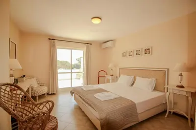 a bedroom with a bed and a chair and a window at FLH Quinta do Lago Retreat with Terrace & Pool in Almancil
