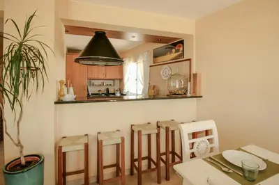 a kitchen with a table and some stools at FLH Quinta do Lago Retreat with Terrace & Pool in Almancil