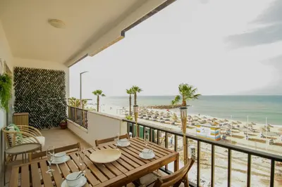a balcony with a table and chairs and the beach at FLH Quarteira Seaview in Quarteira