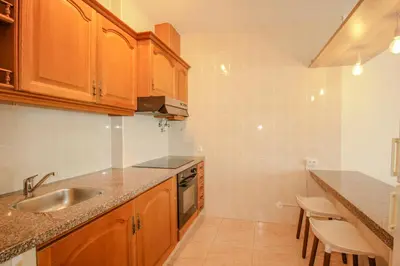 a kitchen with wooden cabinets and a sink at FLH Quarteira Seaview in Quarteira