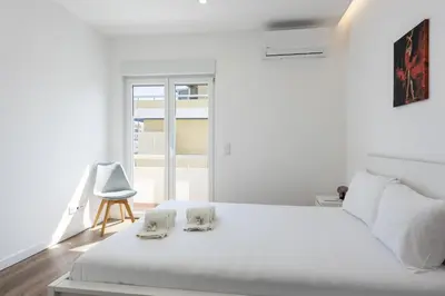 a white bedroom with a white bed and a chair at Garret - Faro Apartment by HD in Faro