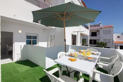 a white table and chairs with an umbrella on a balcony at Casa Flôr in Albufeira