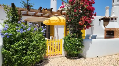 a white house with flowers on the side of it at V2 - Aldeia do Golfe B2 in Quarteira