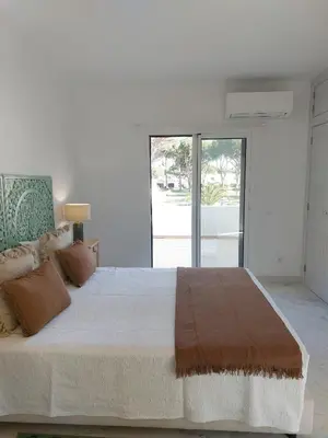 a white bedroom with a large bed and a window at Vilamouratenis Duck by SAPvillas in Vilamoura