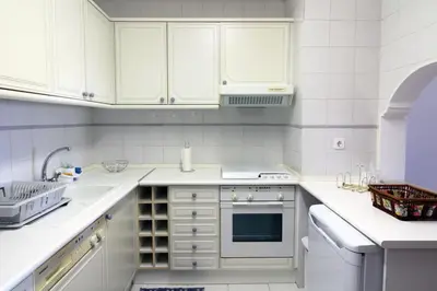 a white kitchen with white cabinets and a sink at Al-Charb Retreat by SAPvillas in Quarteira