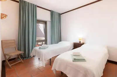 a room with two beds and a chair and a window at Beachtime - Oura Beach Apartment in Albufeira