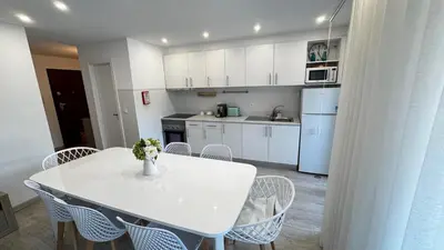 a white kitchen with a white table and chairs at Tenis, Golf e Mar in Quarteira