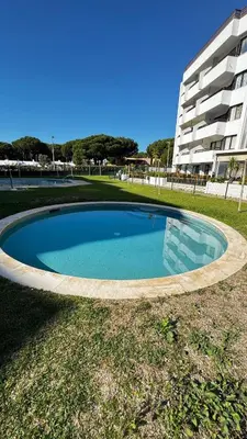 a large swimming pool in front of a building at Tenis, Golf e Mar in Quarteira
