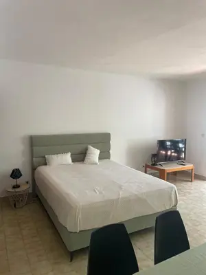 a bedroom with a bed with two chairs and a table at Apartamento em São Rafael in Albufeira