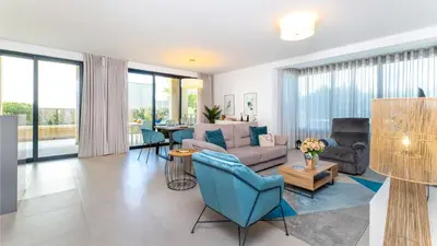 a living room with blue chairs and a couch at Terrazza Beach & Golf in Quarteira