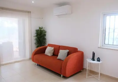 an orange couch in a living room with a window at Bloom Place VALE DO LOBO - Apartamento acolhedor com terraço in Vale do Lobo