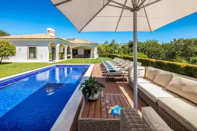 a villa with a swimming pool and an umbrella at Villa Zambujal in Boliqueime