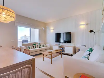 a living room with white furniture and a flat screen tv at Penthouse T4 com Vista Mar em Quarteira in Quarteira