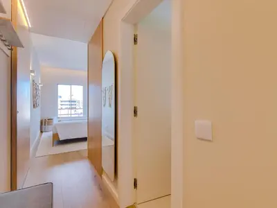 a hallway with white walls and a large mirror at Penthouse T4 com Vista Mar em Quarteira in Quarteira