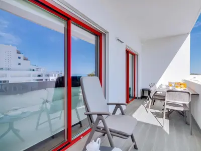 a room with a table and chairs and windows at Penthouse T4 com Vista Mar em Quarteira in Quarteira