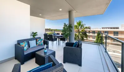 a balcony with couches and a table and chairs at Beach 1Min! & Pool - Private Parking, AC & WiFi in Quarteira