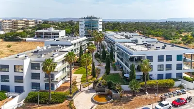 an aerial view of a white building with palm trees at Beach 1Min! & Pool - Private Parking, AC & WiFi in Quarteira