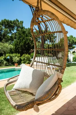 a wicker chair with a pillow on a porch at Villa Sunset,sleeps 9,heatable pool,walk to marina in Vilamoura