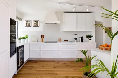 a white kitchen with wooden floors and white cabinets at Casa Rosa dos Ventos in Guia