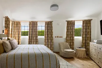 a bedroom with a bed and a chair and windows at Casa Rosa dos Ventos in Guia