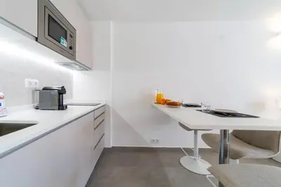 a white kitchen with a table and a microwave at Downtown Apartment - BE by HelloVacations in Albufeira