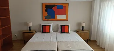 a bedroom with a bed with two lamps and a painting at Faro Station Eleven Guest House in Faro