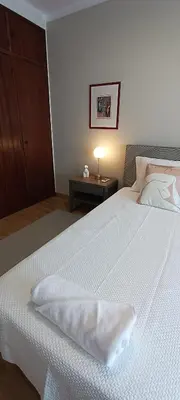 a bedroom with a white bed and a night stand at Faro Station Eleven Guest House in Faro