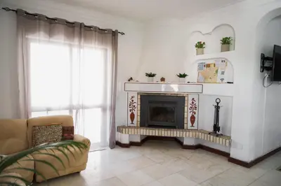 a living room with a fireplace and a chair at Fernando Pessoa Villa in Faro