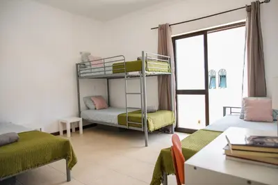a room with two bunk beds with a table and a desk at Fernando Pessoa Villa in Faro