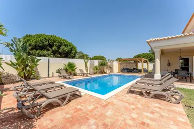 a swimming pool with lounge chairs and a house at Villa Castelo by Algarve Holidays in Albufeira